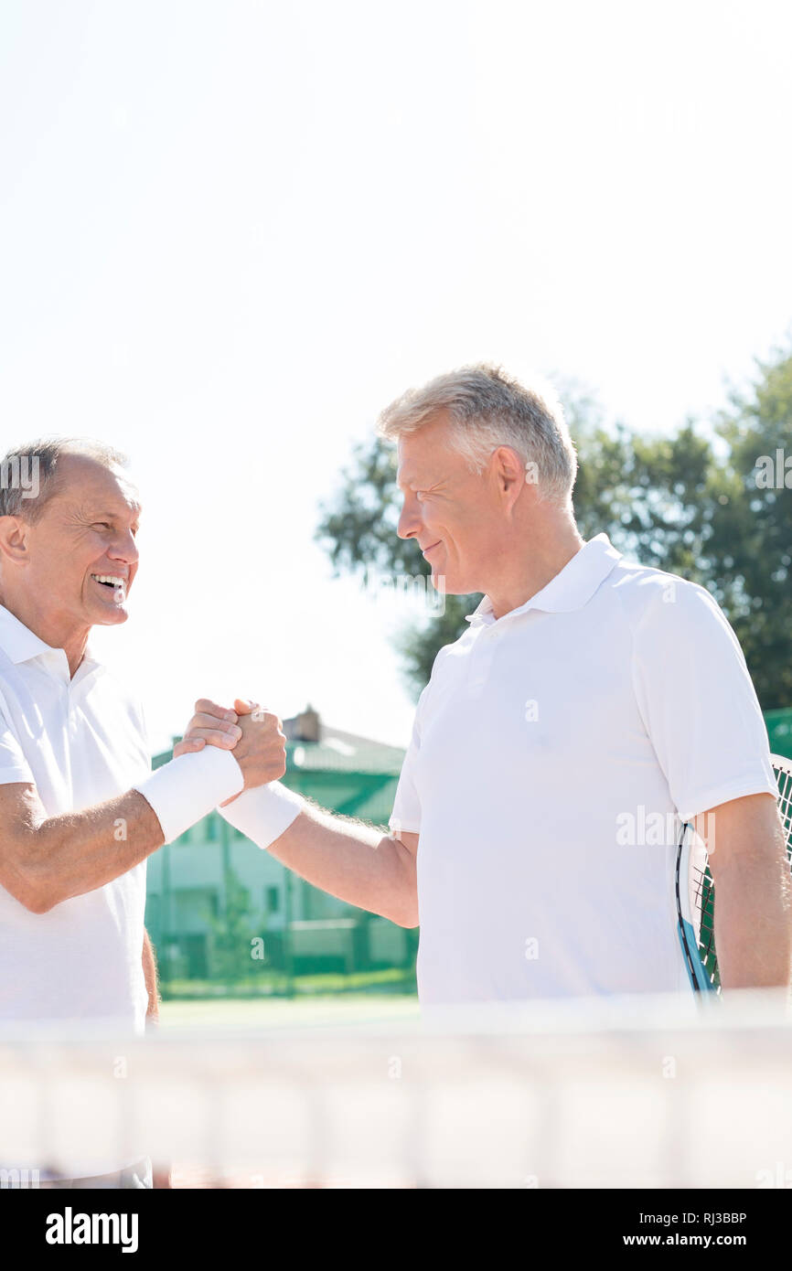 Felici gli uomini saluto mentre si sta in piedi sul campo da tennis durante l estate corrispondono Foto Stock