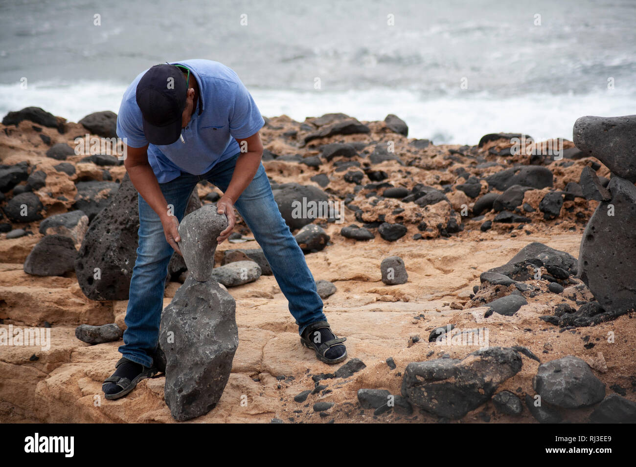 Uomo sulla spiaggia di rocce di bilanciamento. Foto Stock