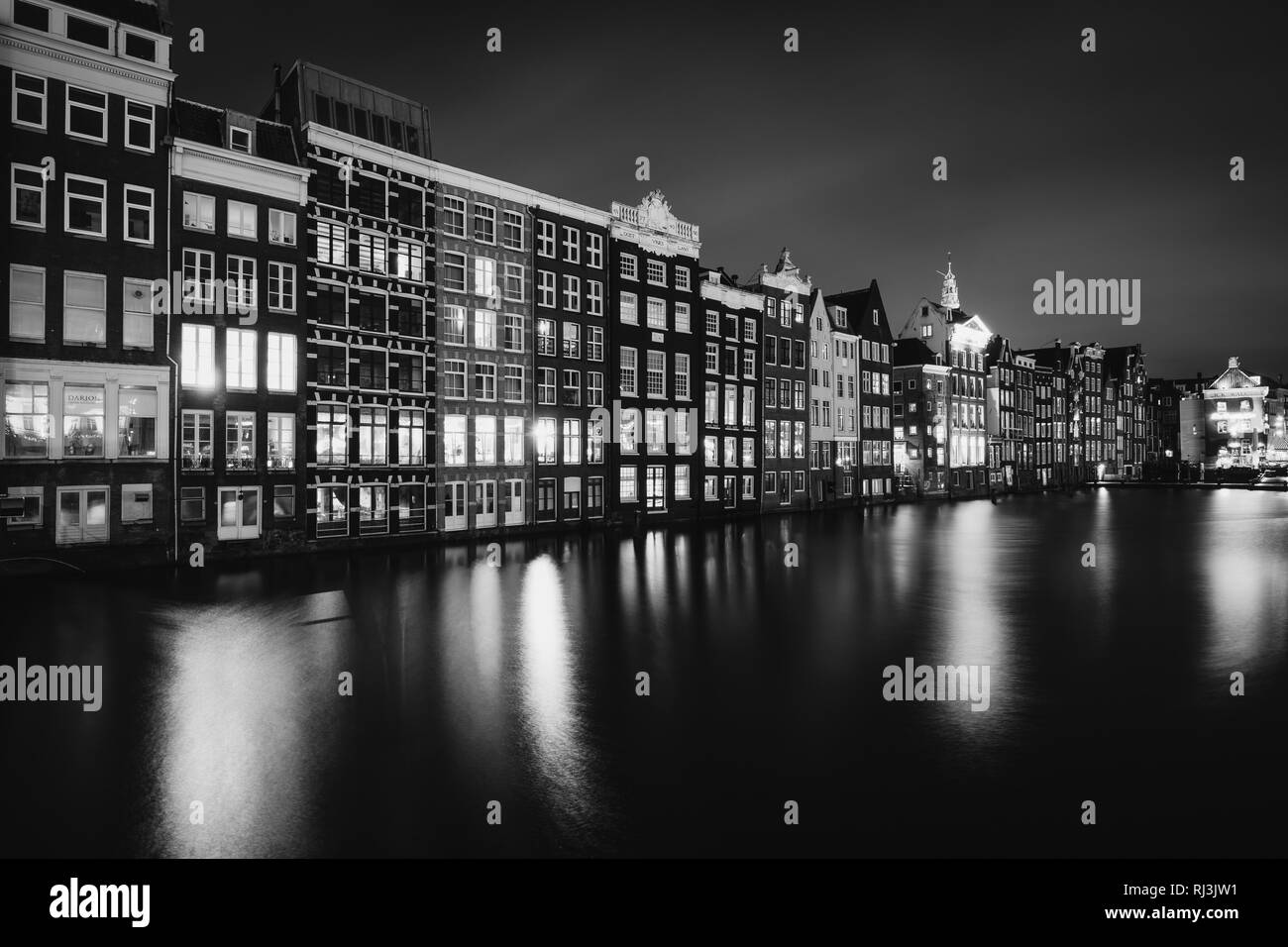 Edifici lungo Damrak canal di notte a Amsterdam, Paesi Bassi. Foto Stock