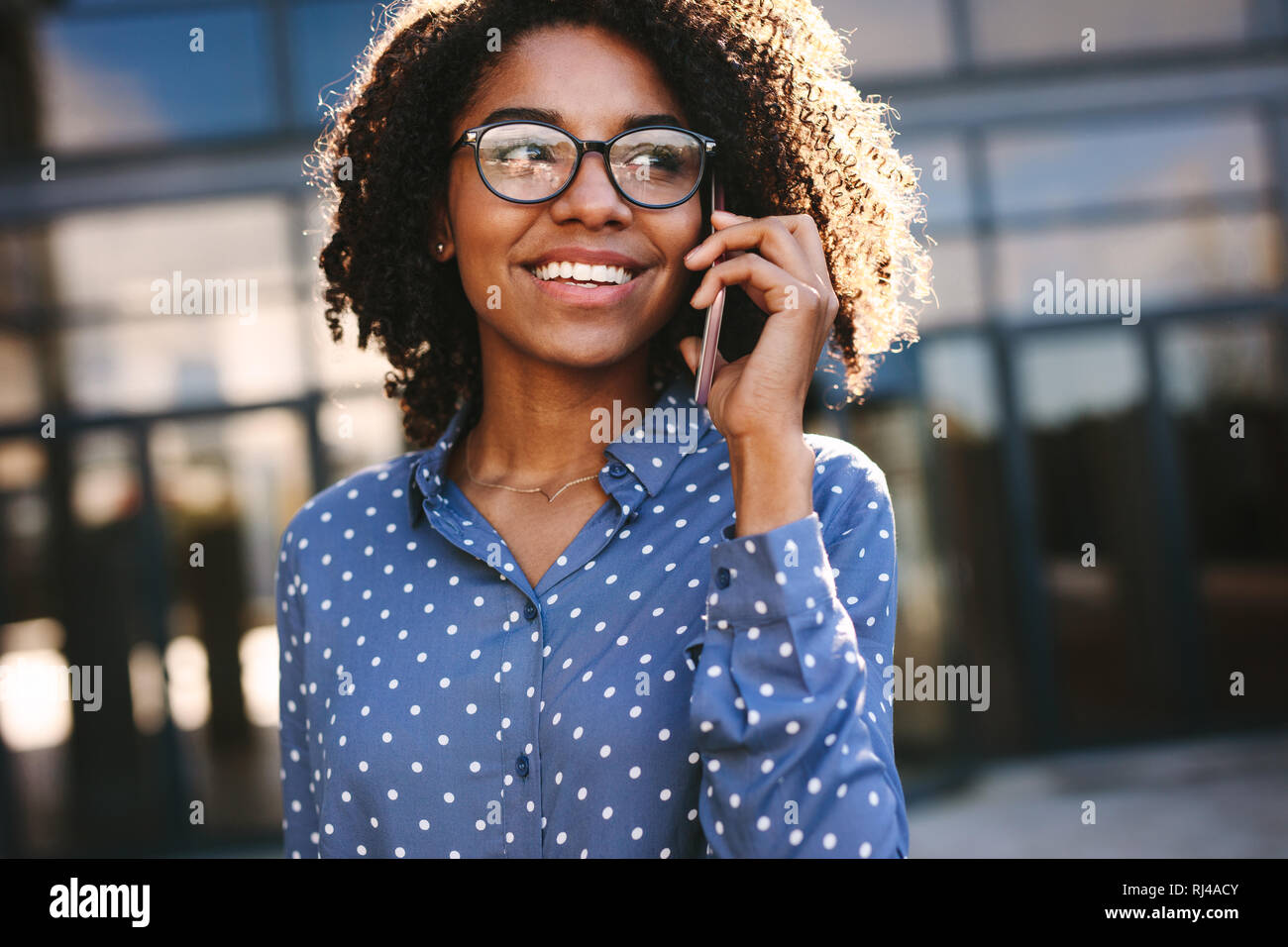 Giovane donna africana passeggiate all'aperto e parlando al cellulare. Close up imprenditrice facendo una telefonata all'esterno. Foto Stock