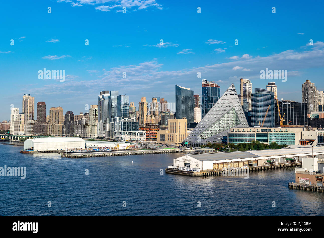 La città di New York skyline di Manhattan con la nave è ormeggiata lungo la costa e via 57 West, una a forma di piramide edificio residenziale da Bjarke Ingels. Foto Stock