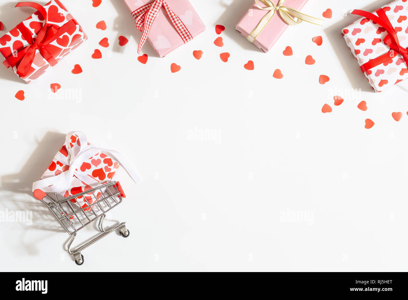 Vacanze di vendita il giorno di San Valentino e Giornata della donna concetto. Carrello della spesa con cuori confezioni regalo. Vista da sopra con spazio copia,stile minimal. Foto Stock