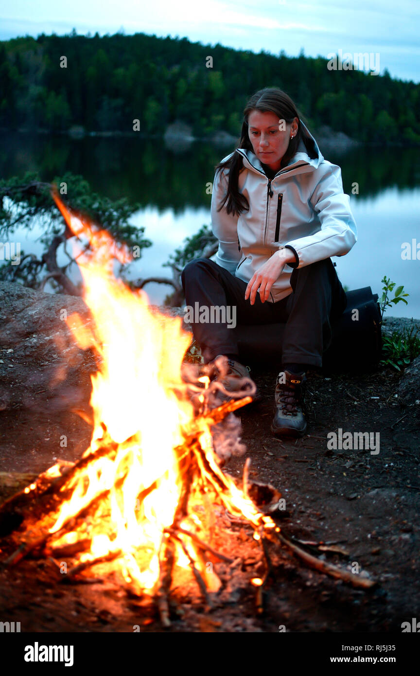 Donna seduta da un incendio Foto Stock
