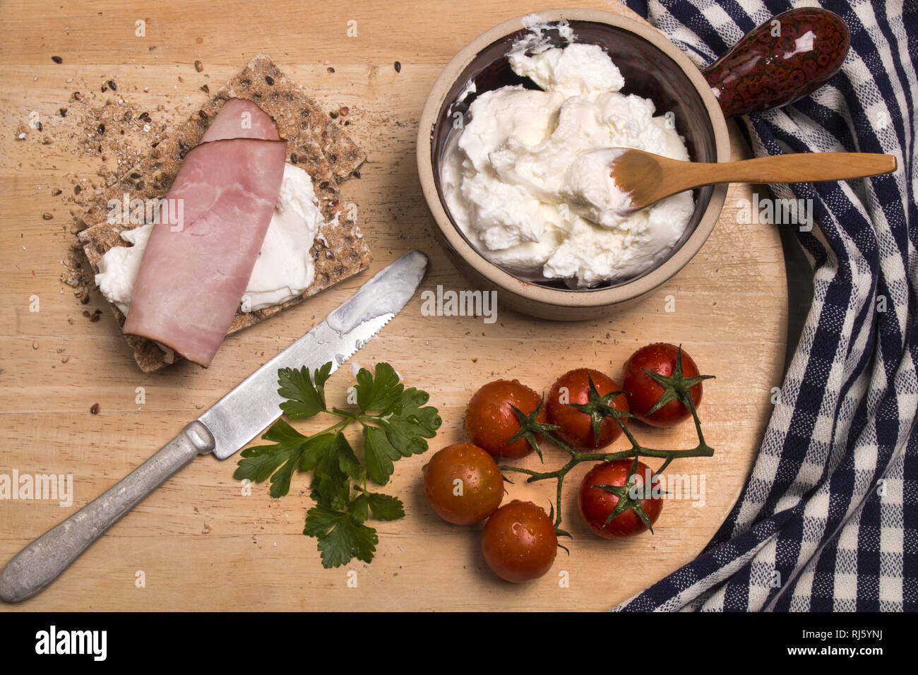 Sana colazione con pane croccante detto Knäckebrot, quark, il prezzemolo e il prosciutto affumicato su una tavola di legno Foto Stock