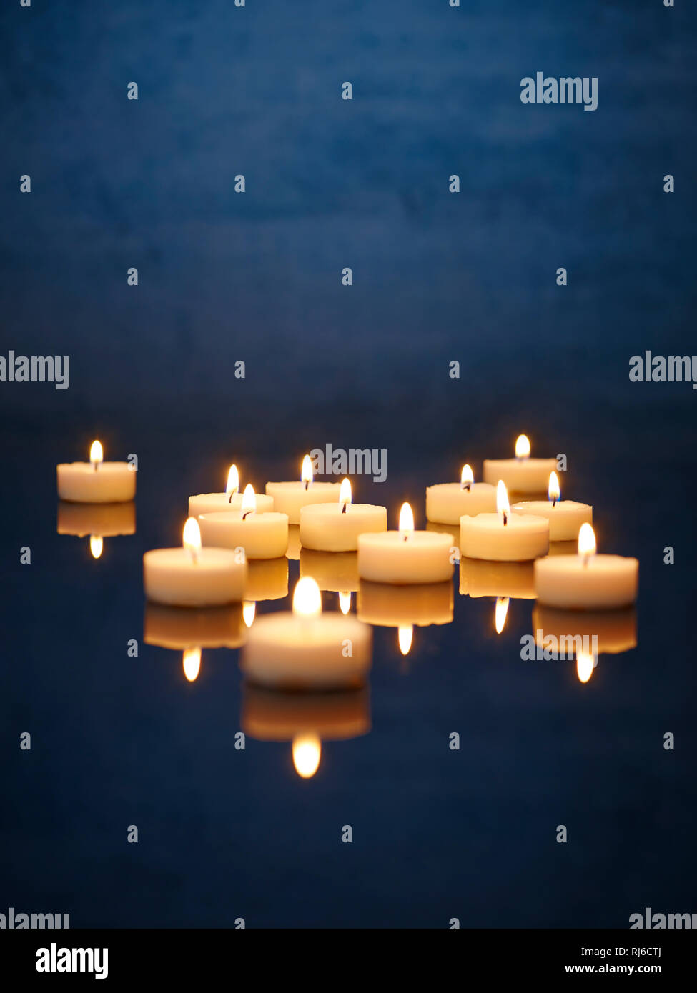 Kerzen mit Spiegelung, angezündet auf einem Tisch Foto Stock