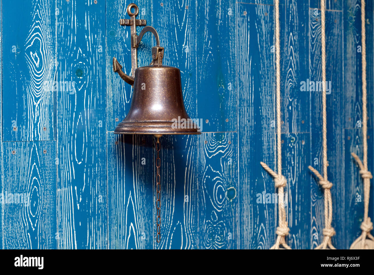 Il rame vecchia campana vintage, campanello, fune su un blu in legno  invecchiato parete. Concetto di elemento di arredamento in interno del  mazzo, cabina di nave, ristorante, sala, casa Foto stock -