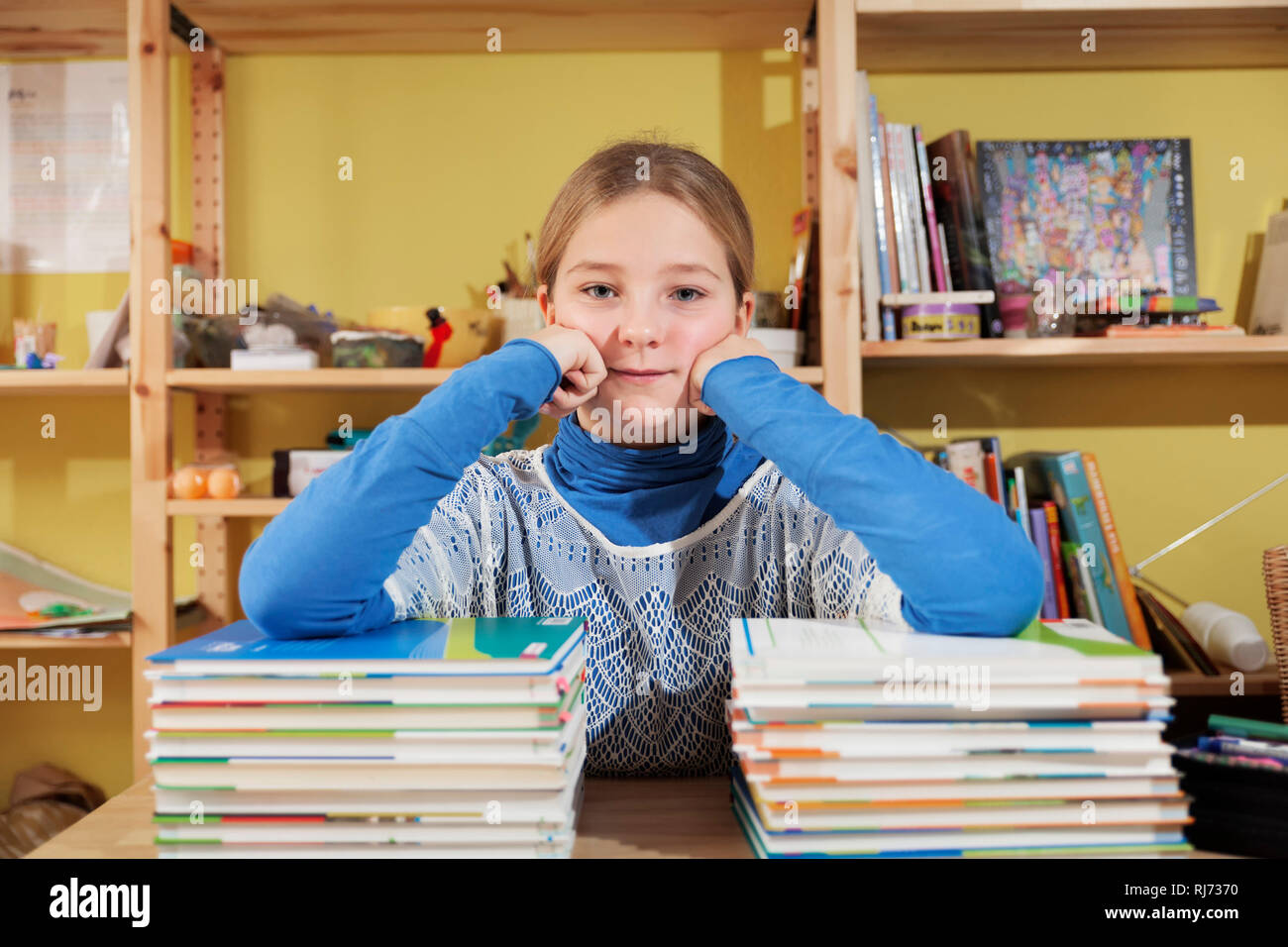 Mädchen, 10 Jahre alt, vor einem Stapel Bücher Foto Stock