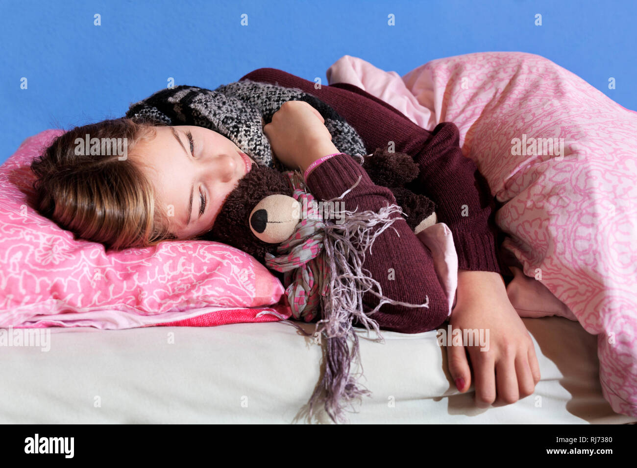Mädchen, 12 Jahre alt, liegt mit Stofftier Bett im, apathisch, deprimiert, krank Foto Stock