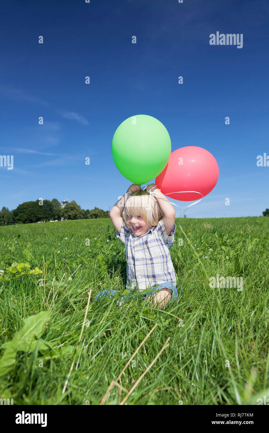 Junge Dreijähriger auf einer Wiese mit Luftballons Foto Stock