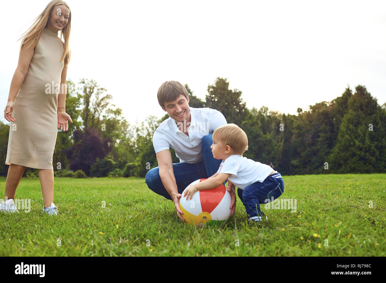 Famiglia con un bambino che gioca con una palla nel parco. Foto Stock