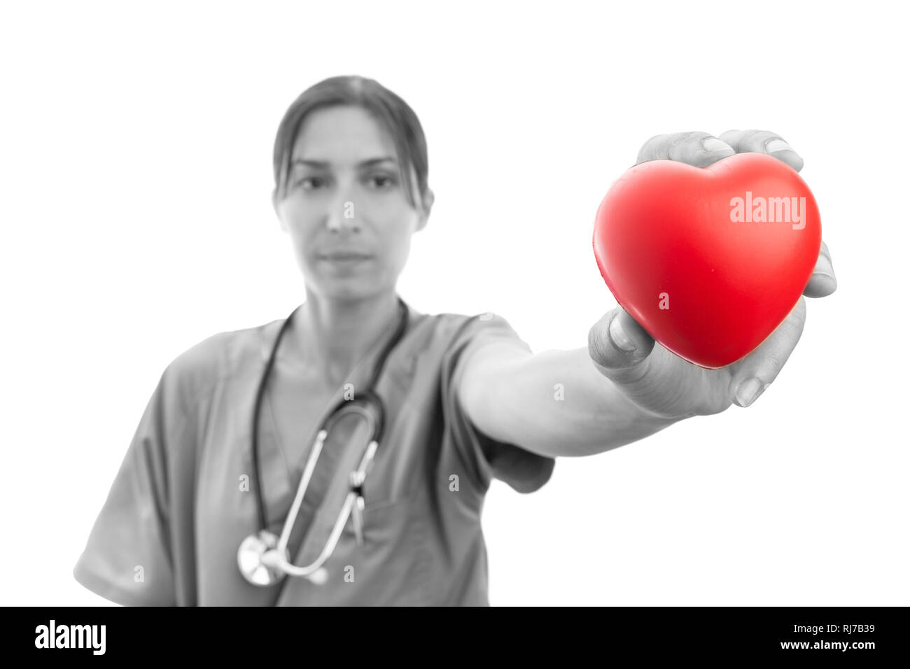 Immagine in bianco e nero di femmina assistente medico presentando Cuore in plastica rosso su sfondo bianco come appassionato per il concetto di cardiologia Foto Stock