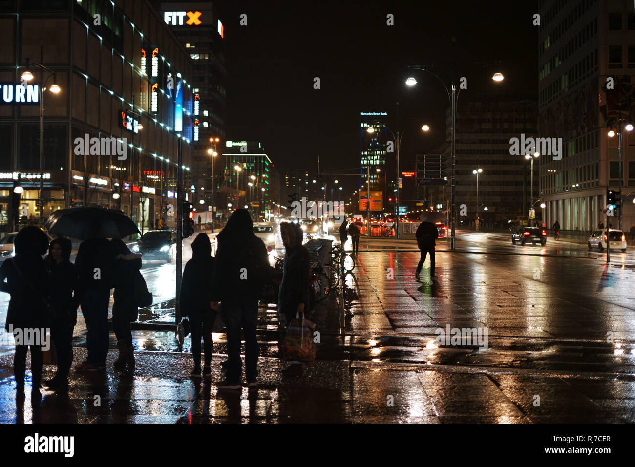 Der Alexanderplatz im Regen mit Kaufhäusern und Einkaufszentren nachts a Berlino. Foto Stock