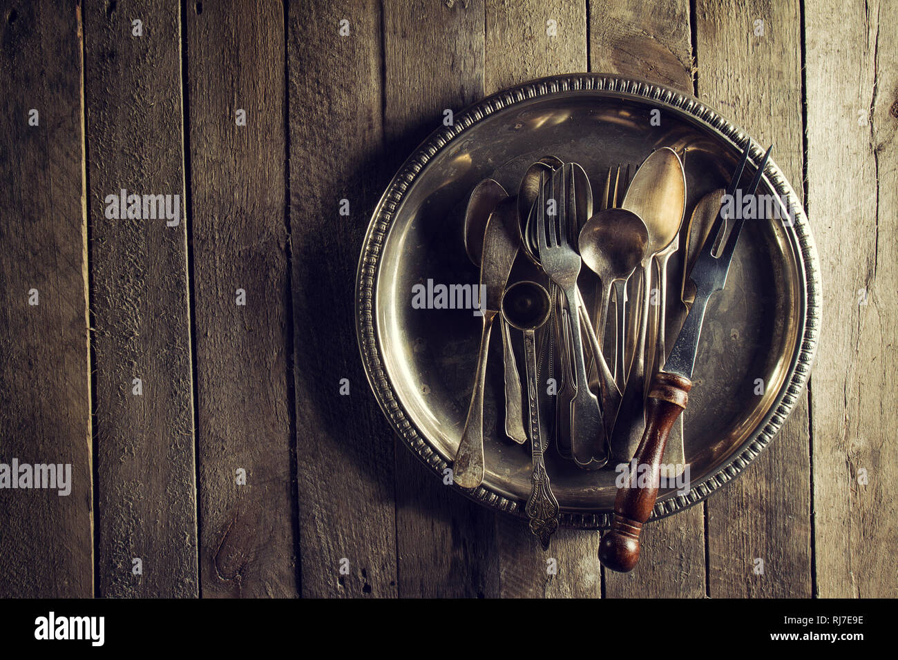 Vintage rustici e vecchi utensili da cucina forchette Cucchiai e coltelli sul vecchio tavolo in legno. Cibo o Vintage concetto rustico. Vista dall'alto. Foto Stock