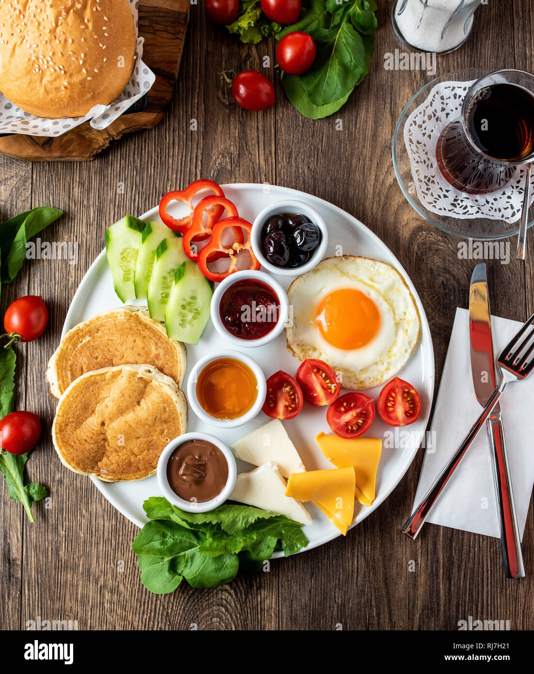 Enorme sana colazione spalmato su una tabella con caffè, tè, pomodoro, uova, pancake, marmellata e formaggio, Foto Stock