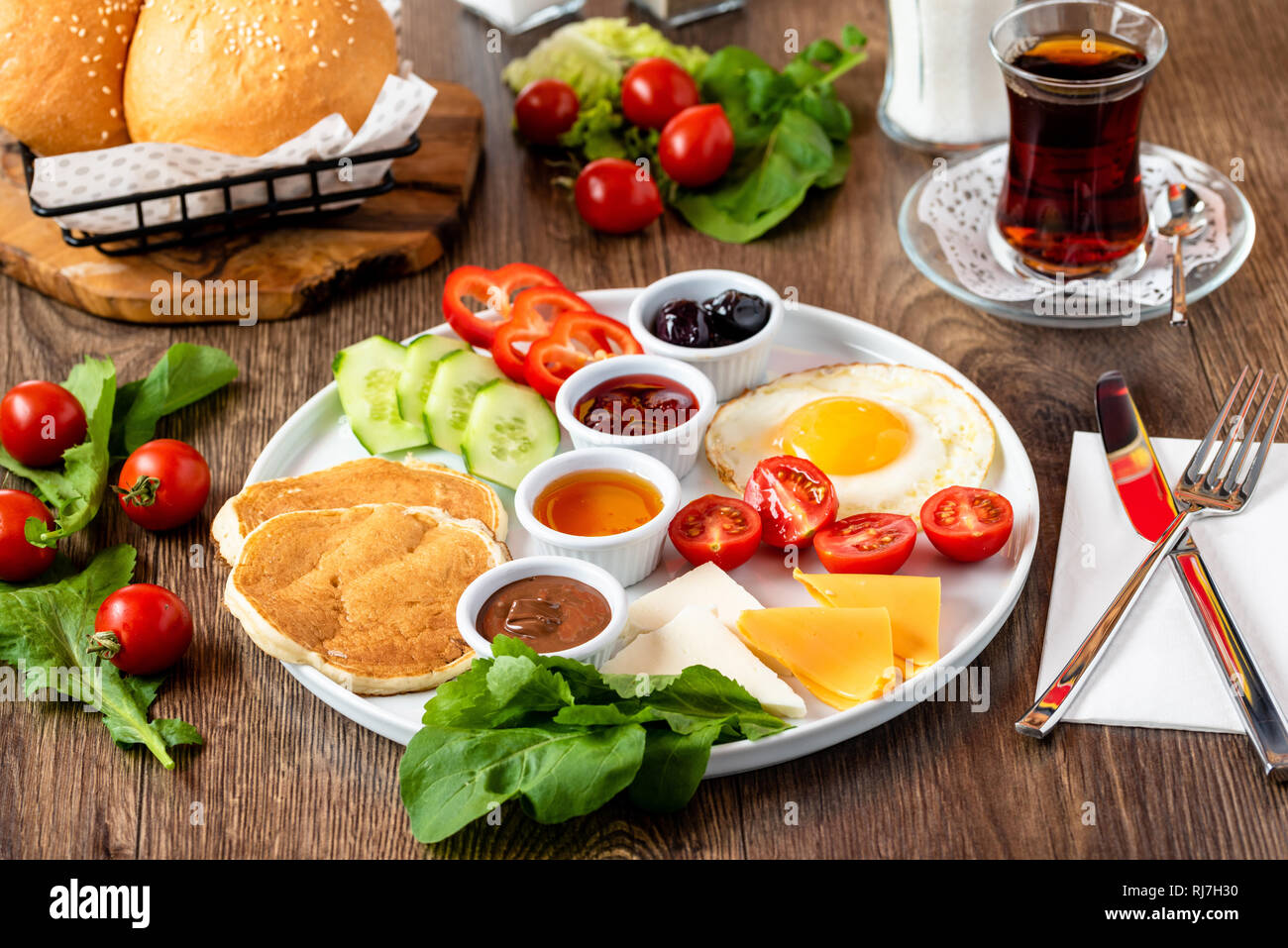 Enorme sana colazione spalmato su una tabella con caffè, tè, pomodoro, uova, pancake, marmellata e formaggio, Foto Stock