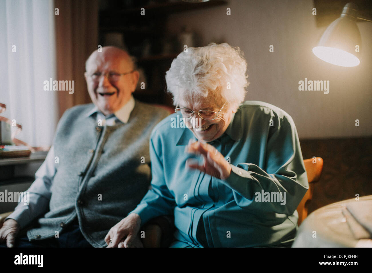 Seniorenpaar lachend sitzt im Wohnzimmer Foto Stock