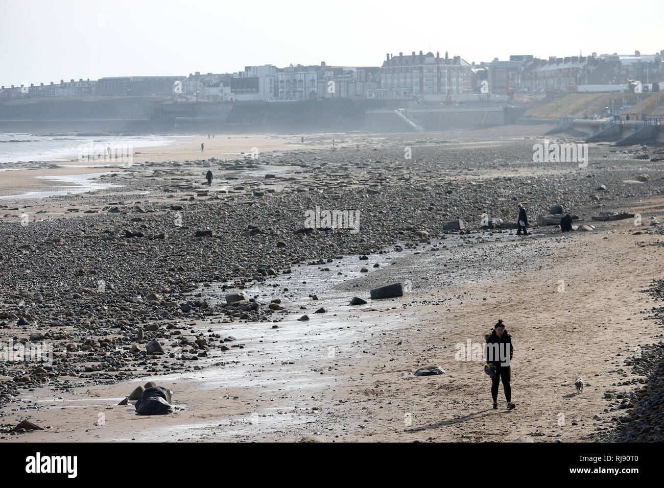 Whitley Bay spiaggia coperta in pietre e rocce dopo le recenti intemperie, giovedì 8 marzo 2018. Foto Stock