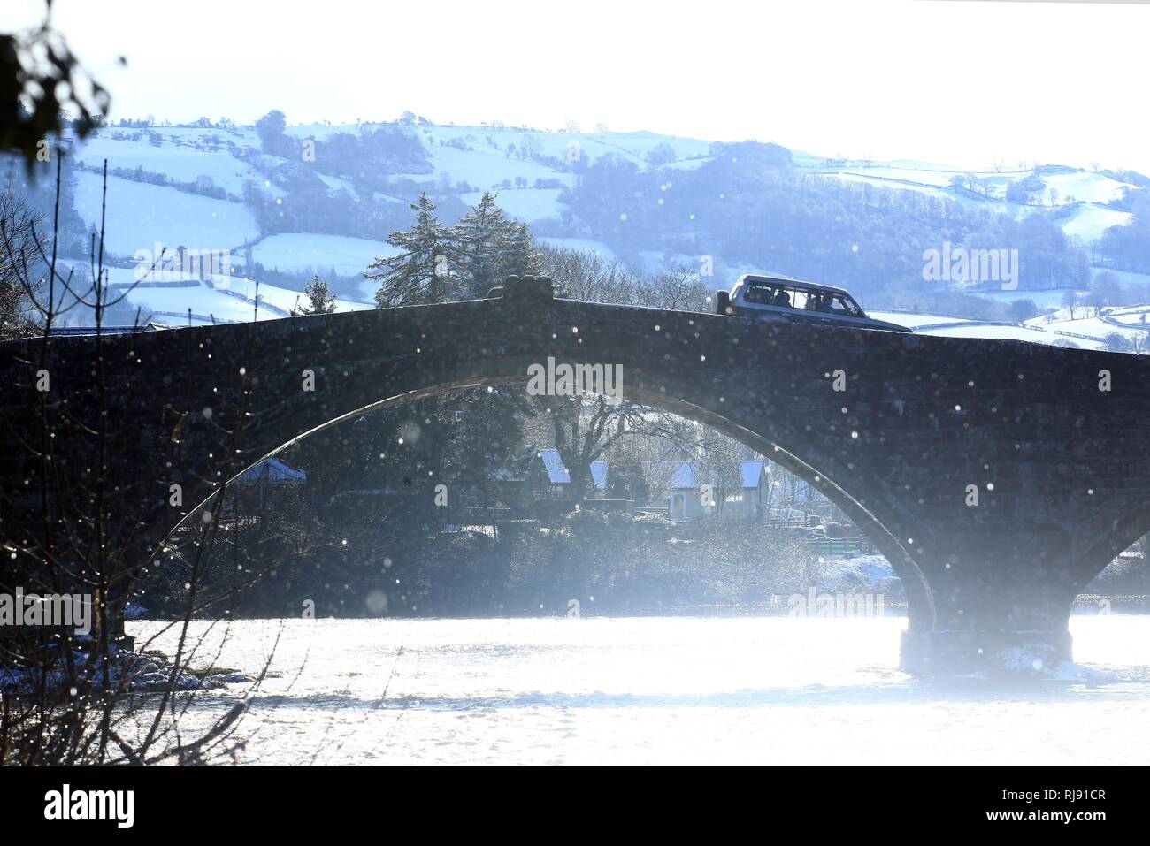 Una vettura attraversa Pont Fawr a Llanrwst con coperta di neve di colline in background. Giovedì 8 marzo 2018. Foto Stock