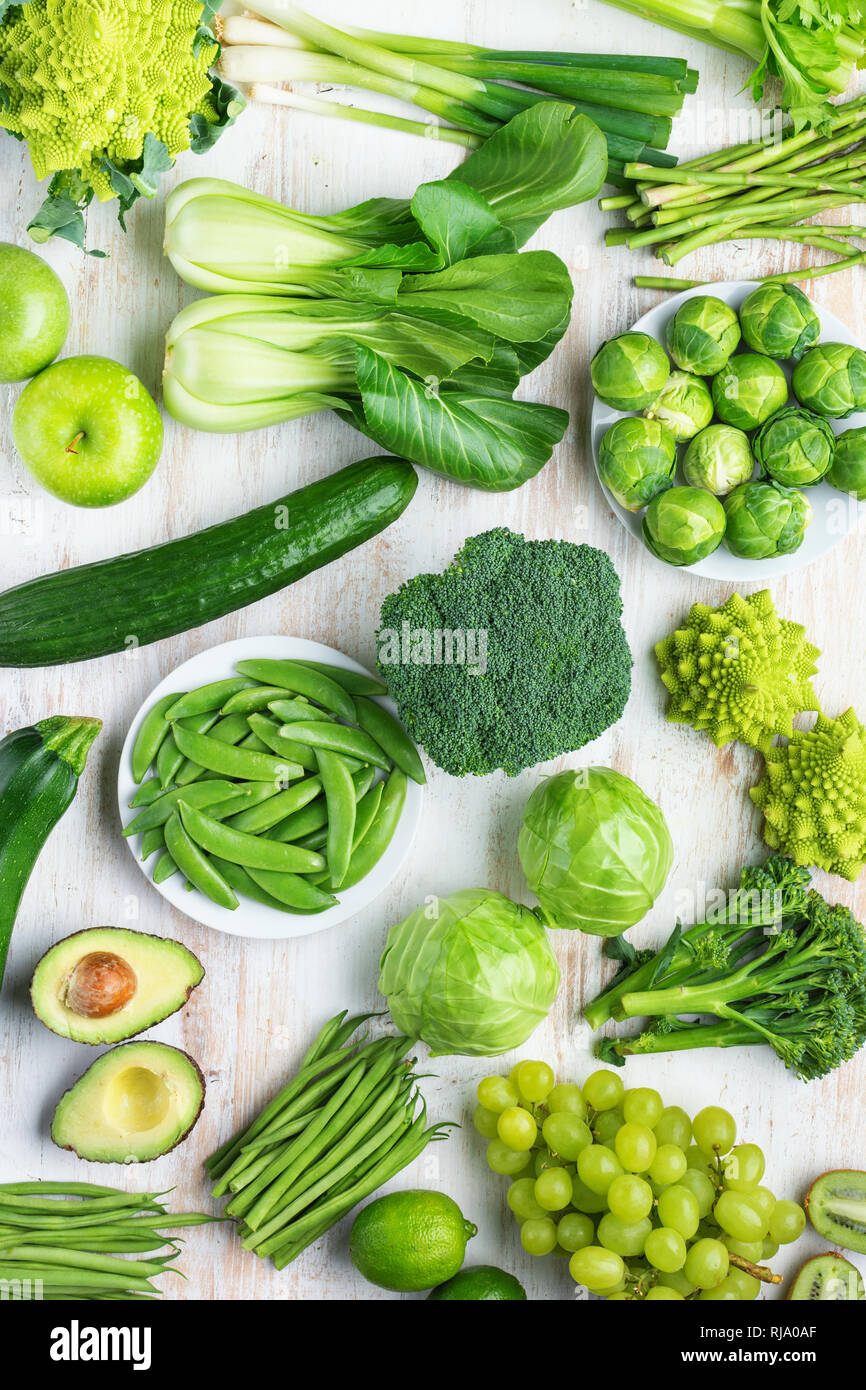 Mangiare sano concetto vegan. Verdure verdi frutti sul tavolo bianco broccoletti piselli avocado fagioli zucchine cavolo cinese sedano mela uva, top v Foto Stock