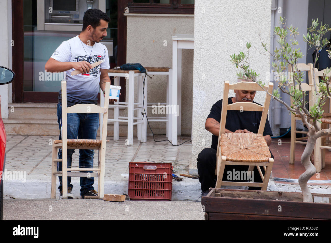 Due uomini sedie di ripristino sulla strada in Grecia Foto Stock