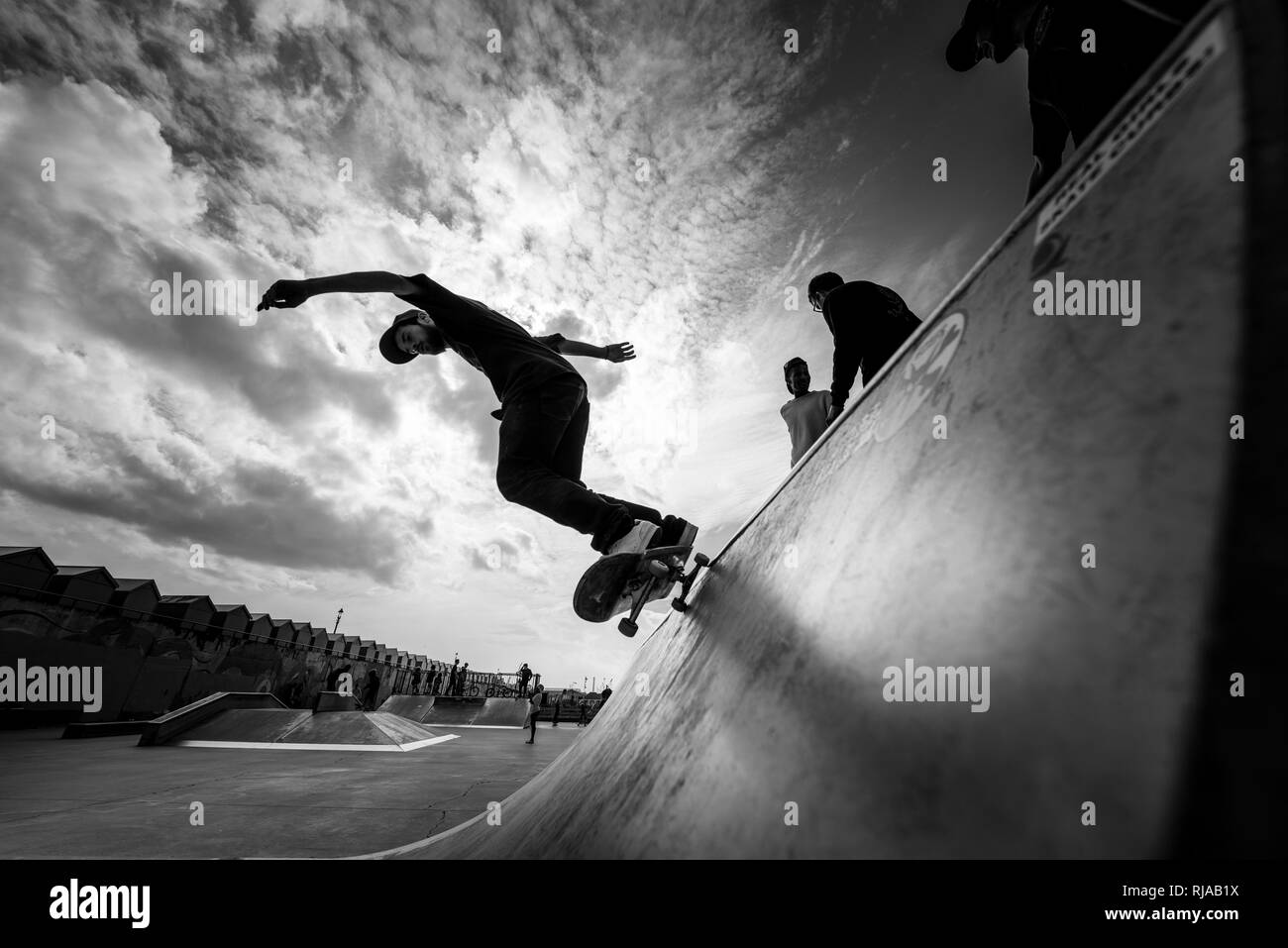 Un uomo pattinaggio esegue un trucco su una rampa a Hove Lagoon Skatepark, Hove, Brighton, Inghilterra. Foto Stock