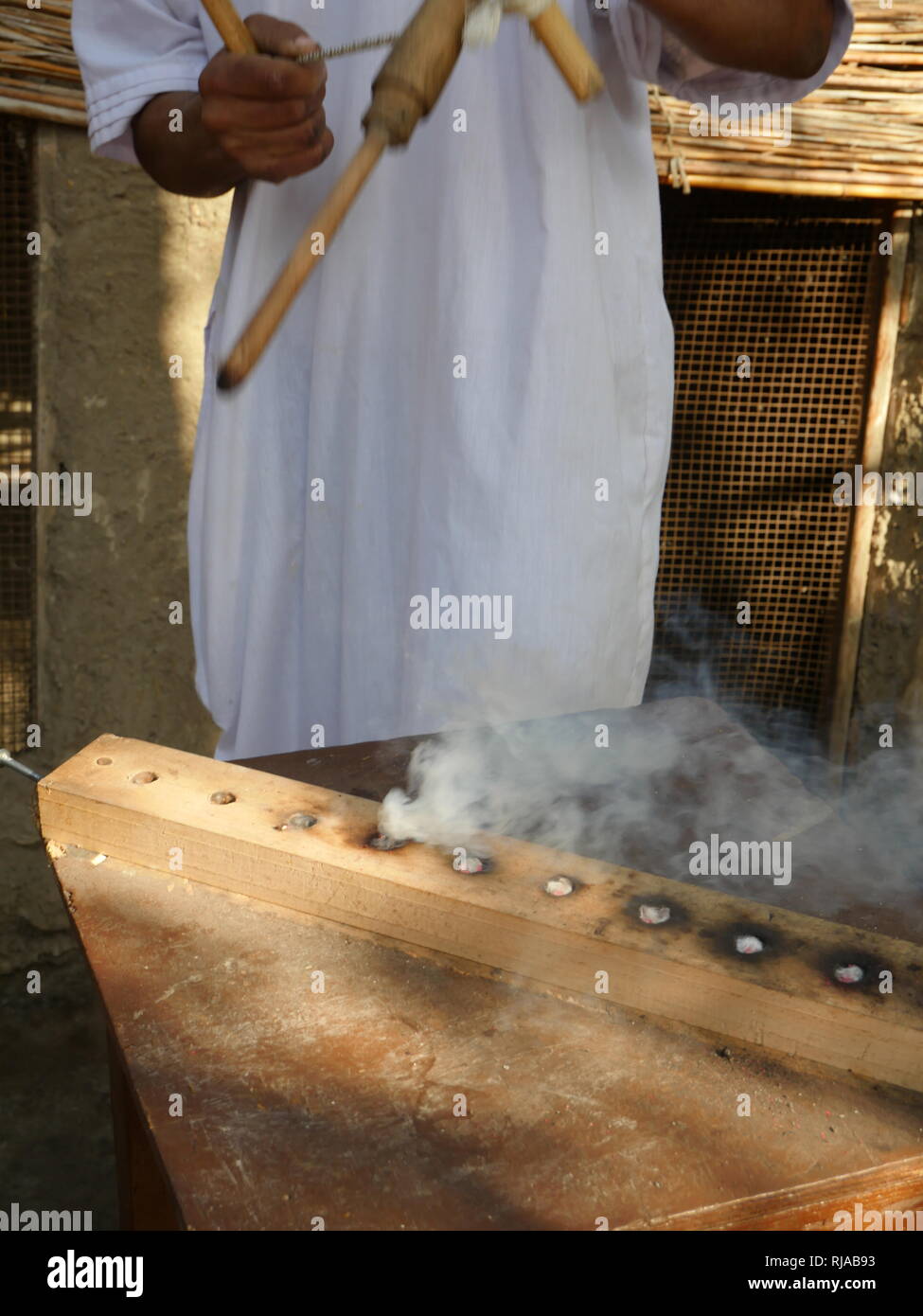 Ri-attuato scena di antichi Egiziani il fuoco che fa, utilizzando un trapano e metodo di attrito a scintilla di calore e di creare una fiamma Foto Stock