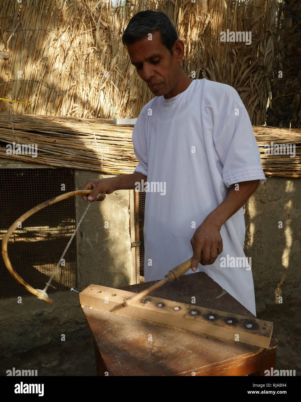 Ri-attuato scena di antichi Egiziani il fuoco che fa, utilizzando un trapano e metodo di attrito a scintilla di calore e di creare una fiamma Foto Stock