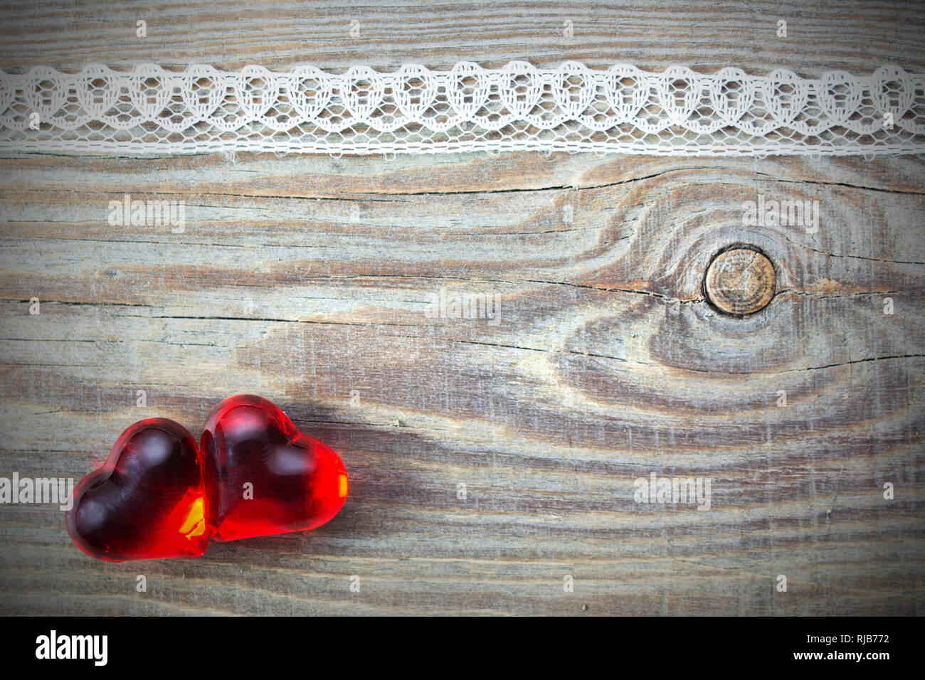 Valentino, scheda di nozze sfondo con due cuori di vetro su di un asse di legno con un nodo e pizzo Foto Stock