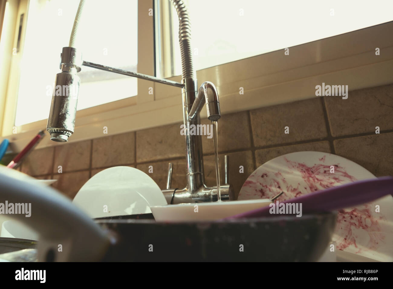 Un mucchio disordinato di piatti sporchi e utensili in lavello da cucina Foto Stock