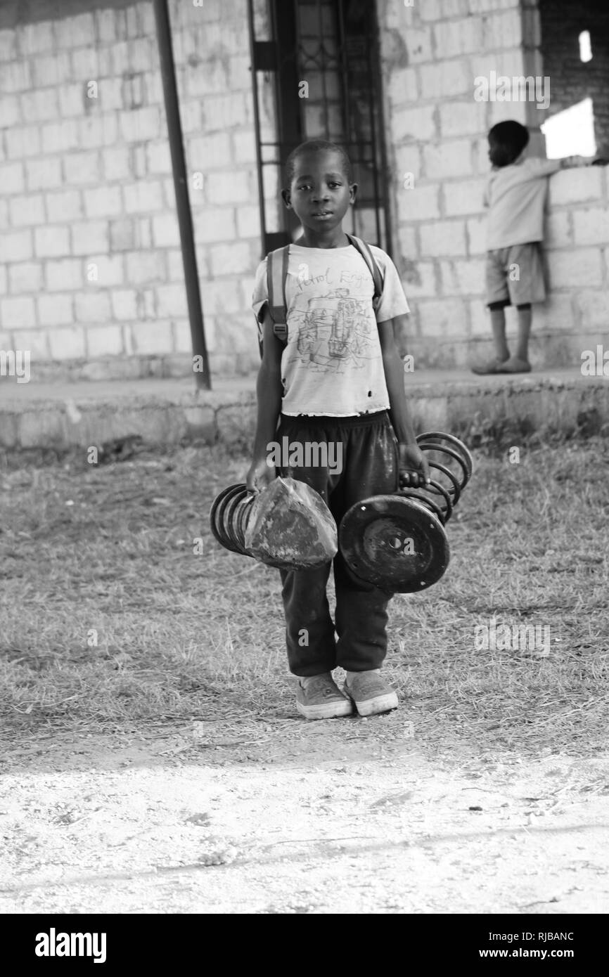 Ragazzo tenendo sedie per sedersi a scuola Zambia B&W Foto Stock