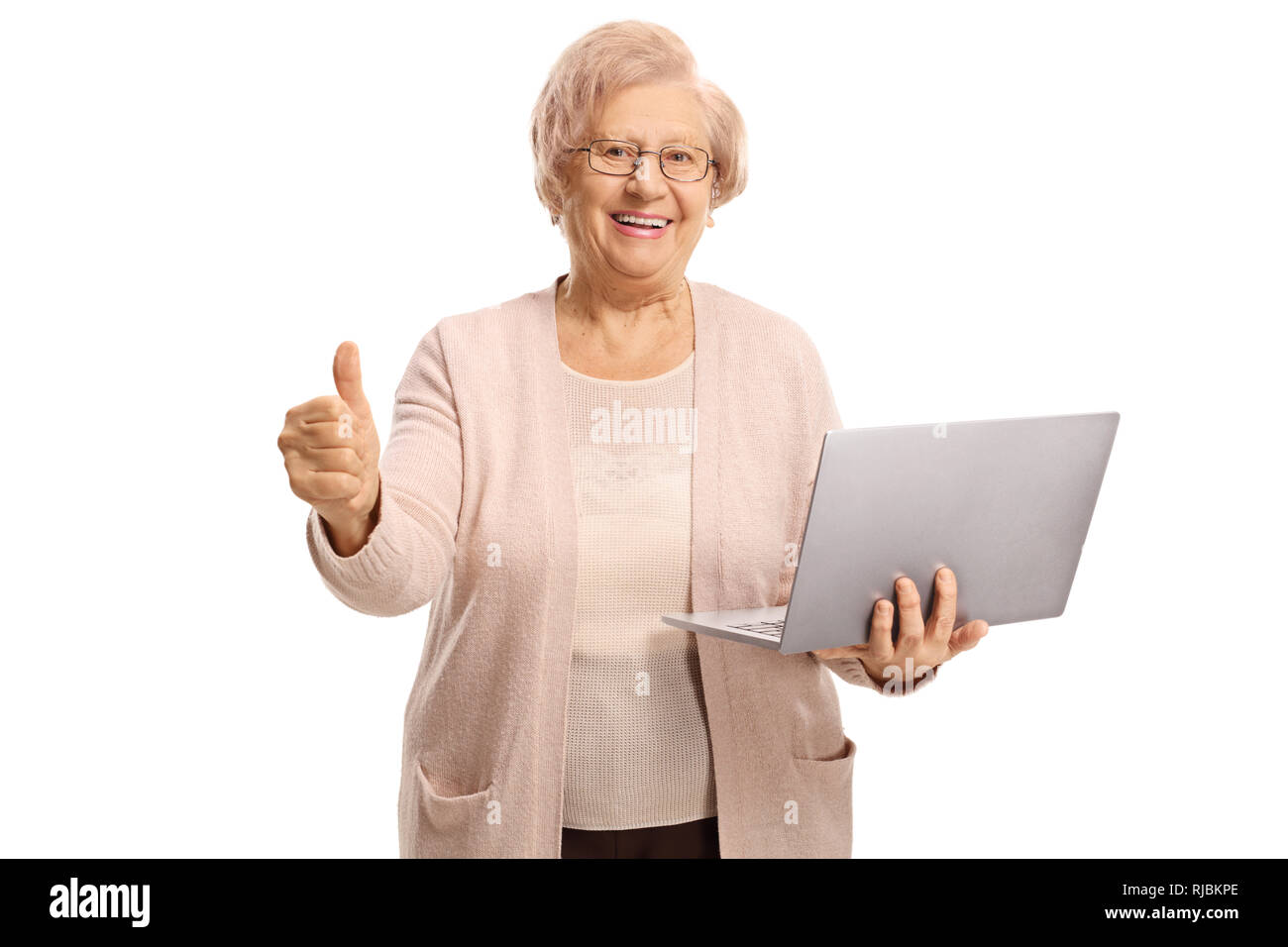 Felice donna senior in possesso di un computer portatile e mostrando pollice in alto isolato su sfondo bianco Foto Stock