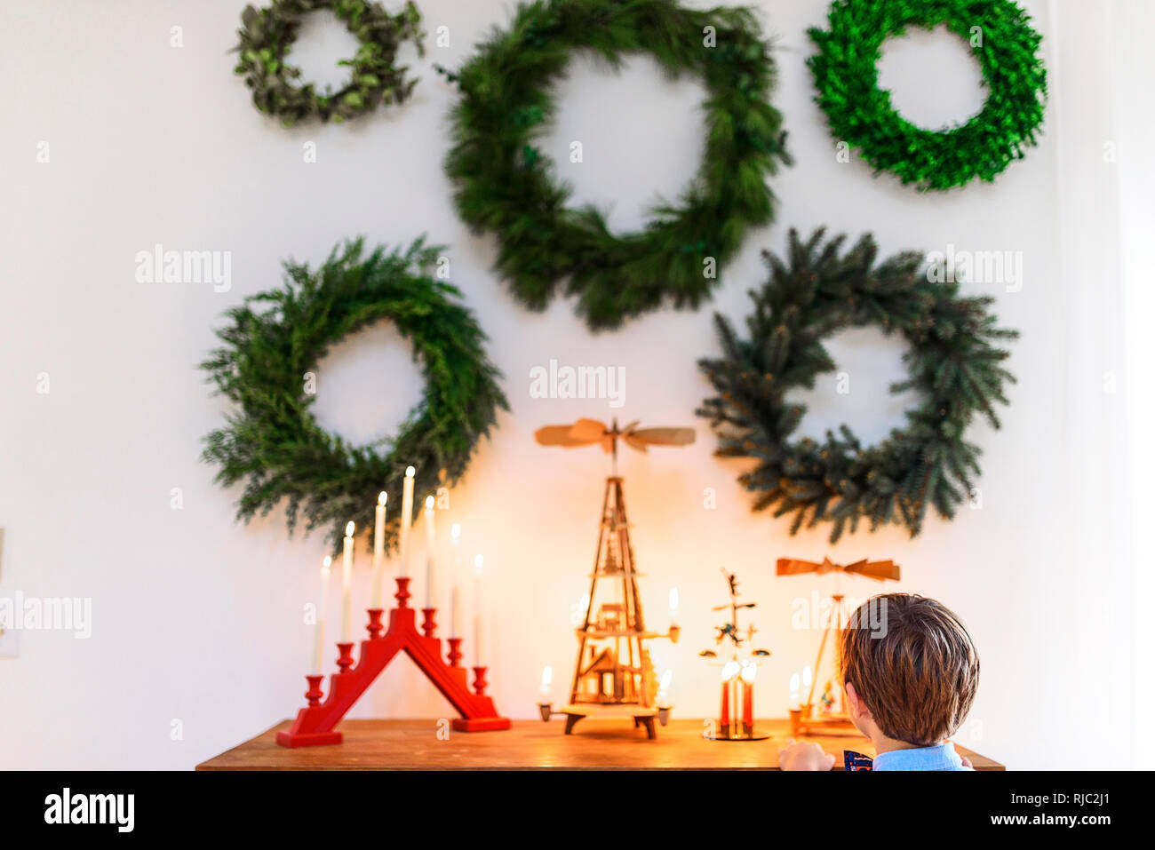 Ragazzo in piedi di fronte ad una credenza guardando le decorazioni di Natale Foto Stock