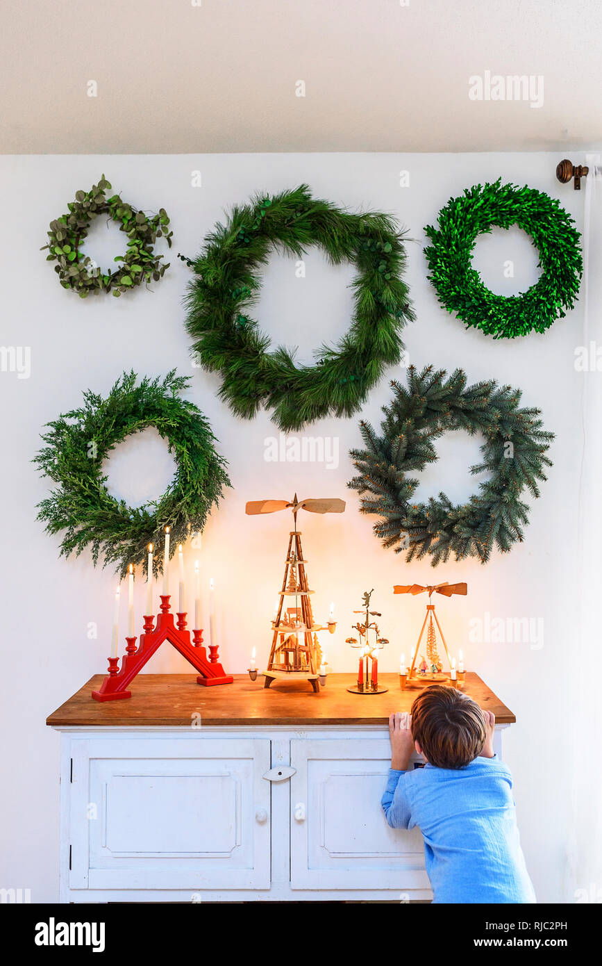 Ragazzo in piedi di fronte ad una credenza guardando le decorazioni di Natale Foto Stock