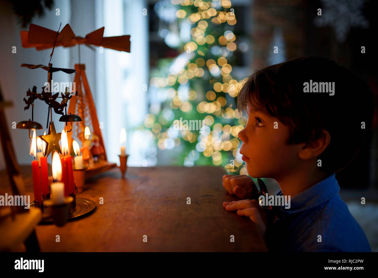 Ragazzo in piedi di fronte ad una credenza guardando le decorazioni di Natale Foto Stock