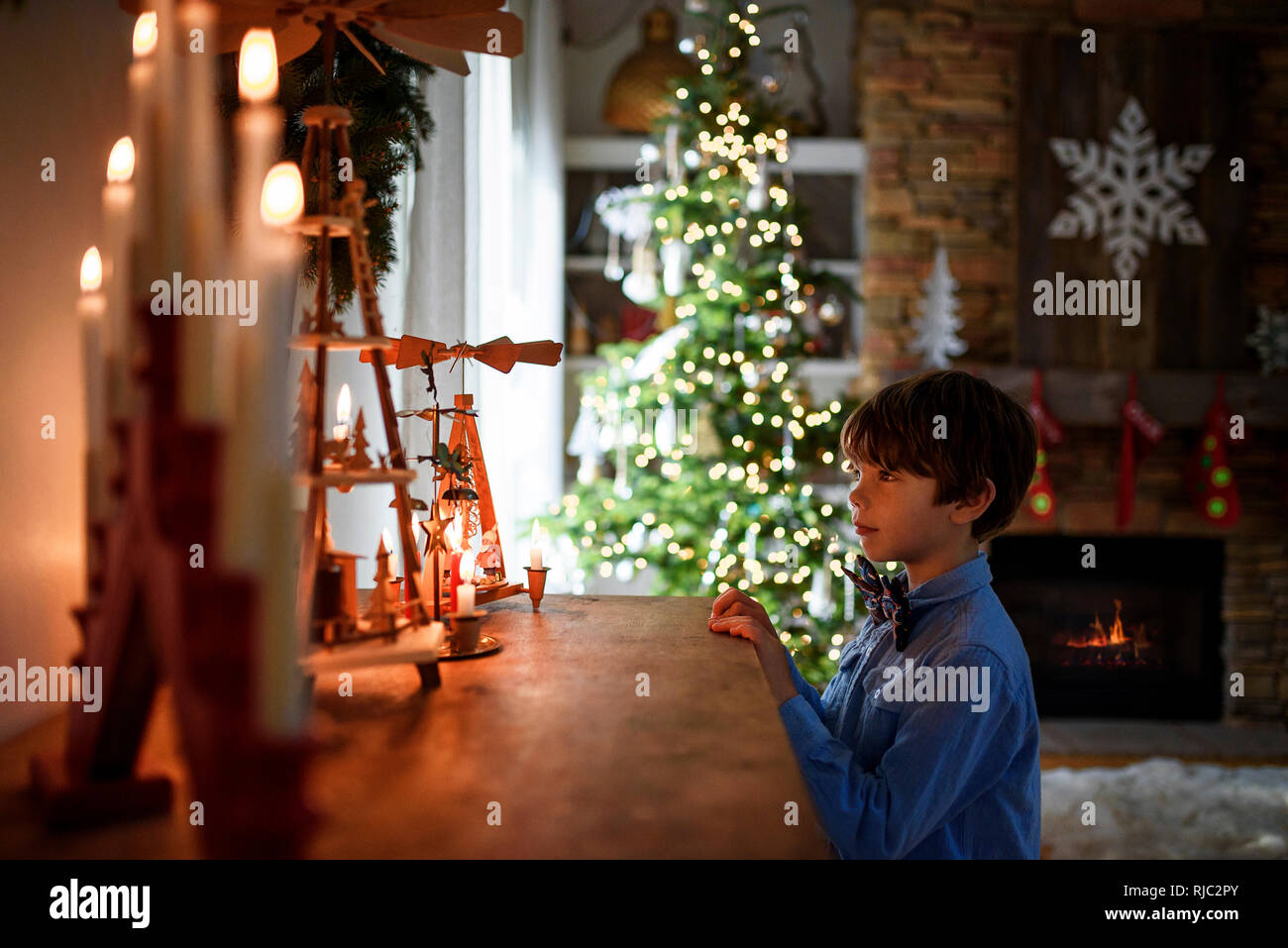 Ragazzo in piedi di fronte ad una credenza guardando le decorazioni di Natale Foto Stock
