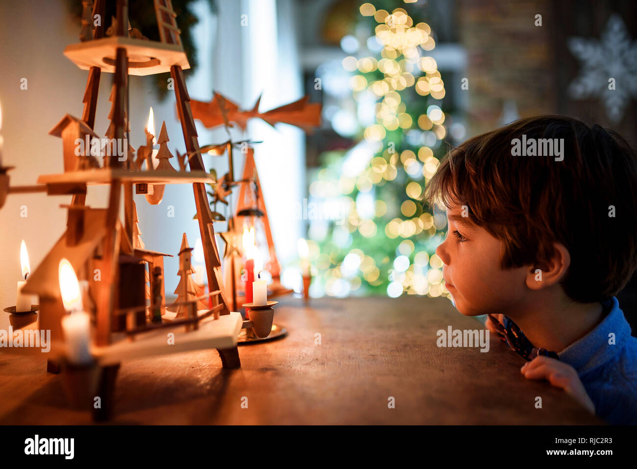 Ragazzo in piedi di fronte ad una credenza guardando le decorazioni di Natale Foto Stock