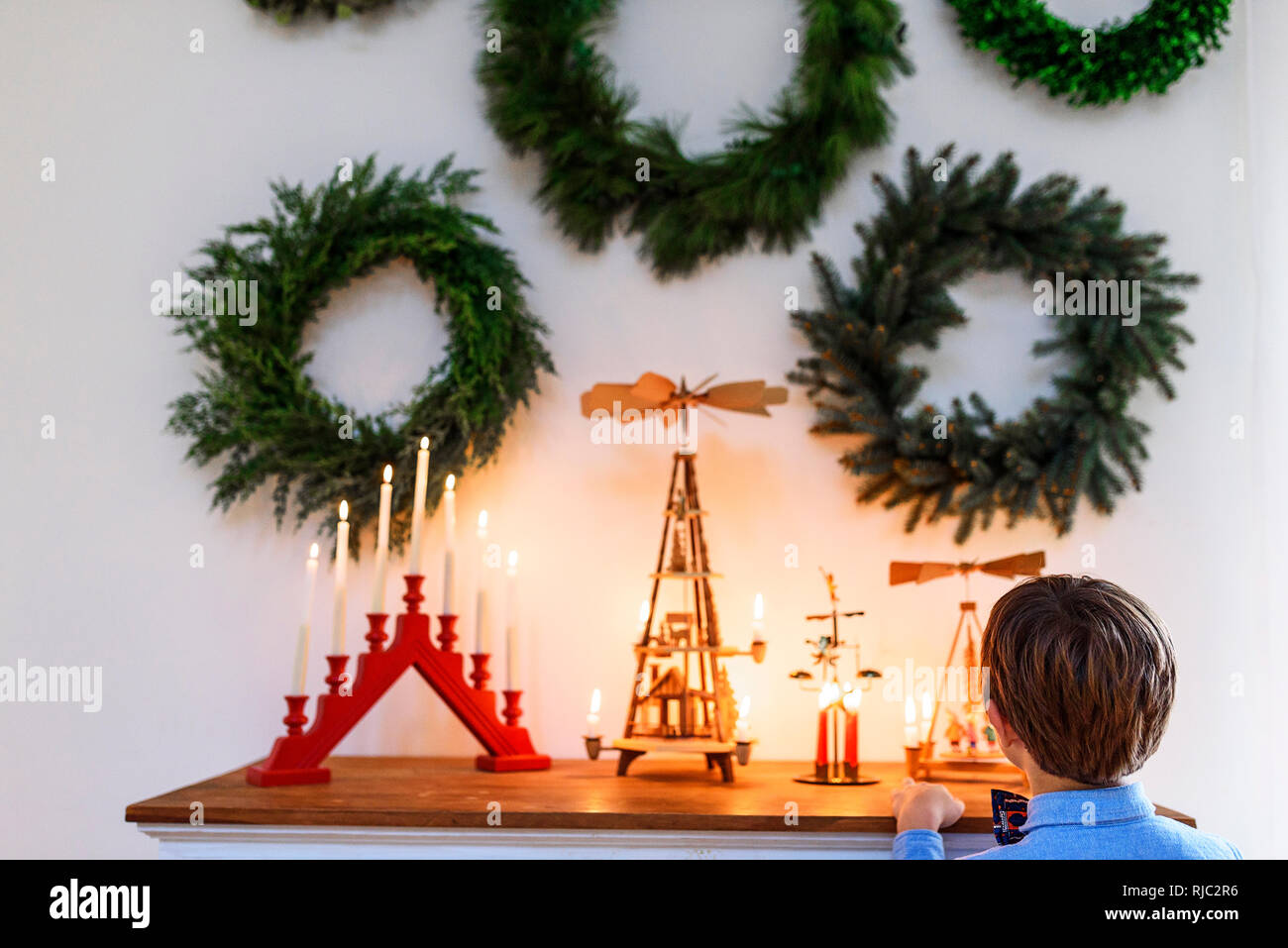 Ragazzo in piedi di fronte ad una credenza guardando le decorazioni di Natale Foto Stock
