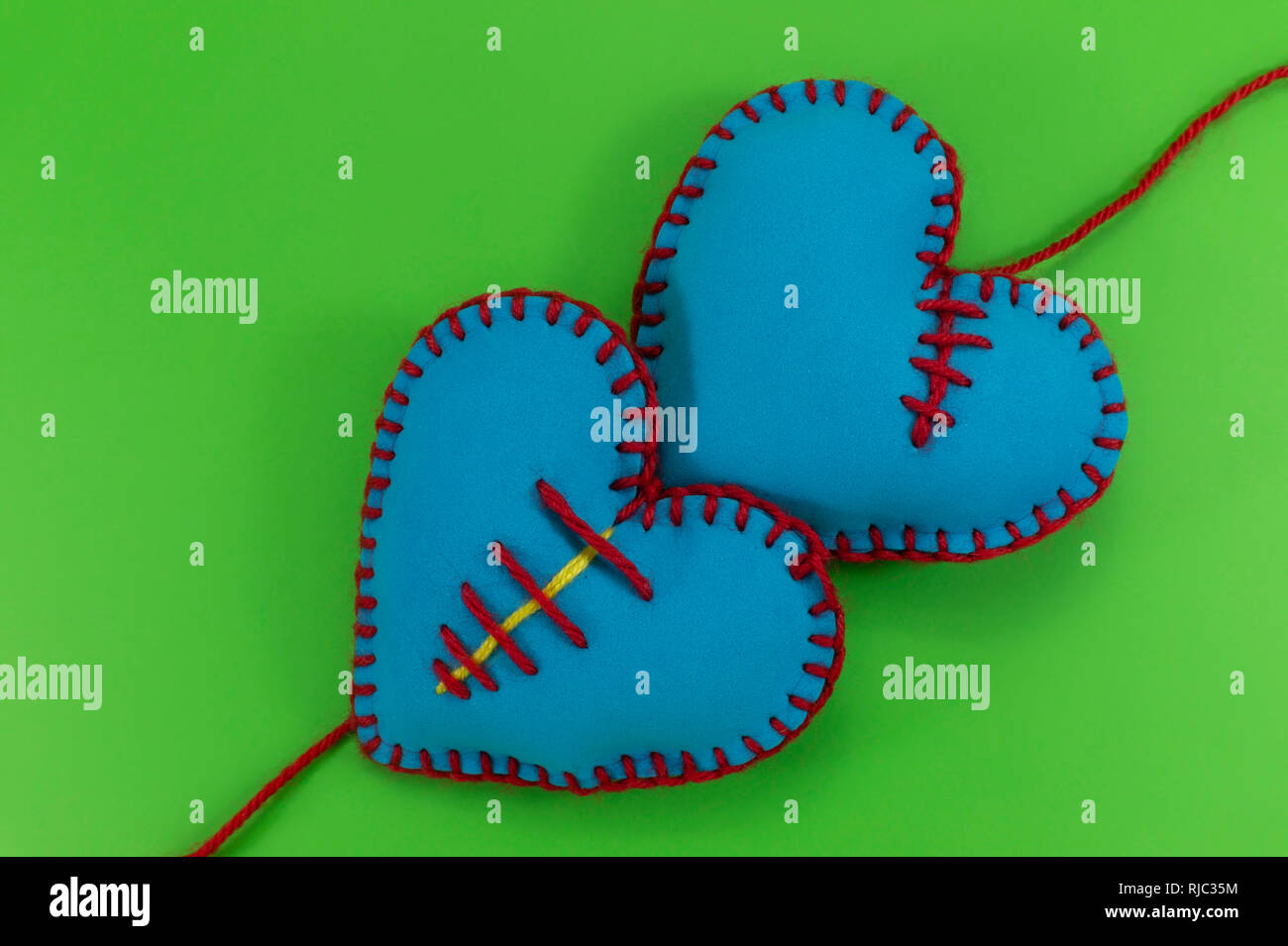 A forma di cuore cucito a mano cuori tessili realizzati in tessuto blu e cucita con fili rossi sul verde Chroma Key per sfondo romantico o Valentines conc Foto Stock