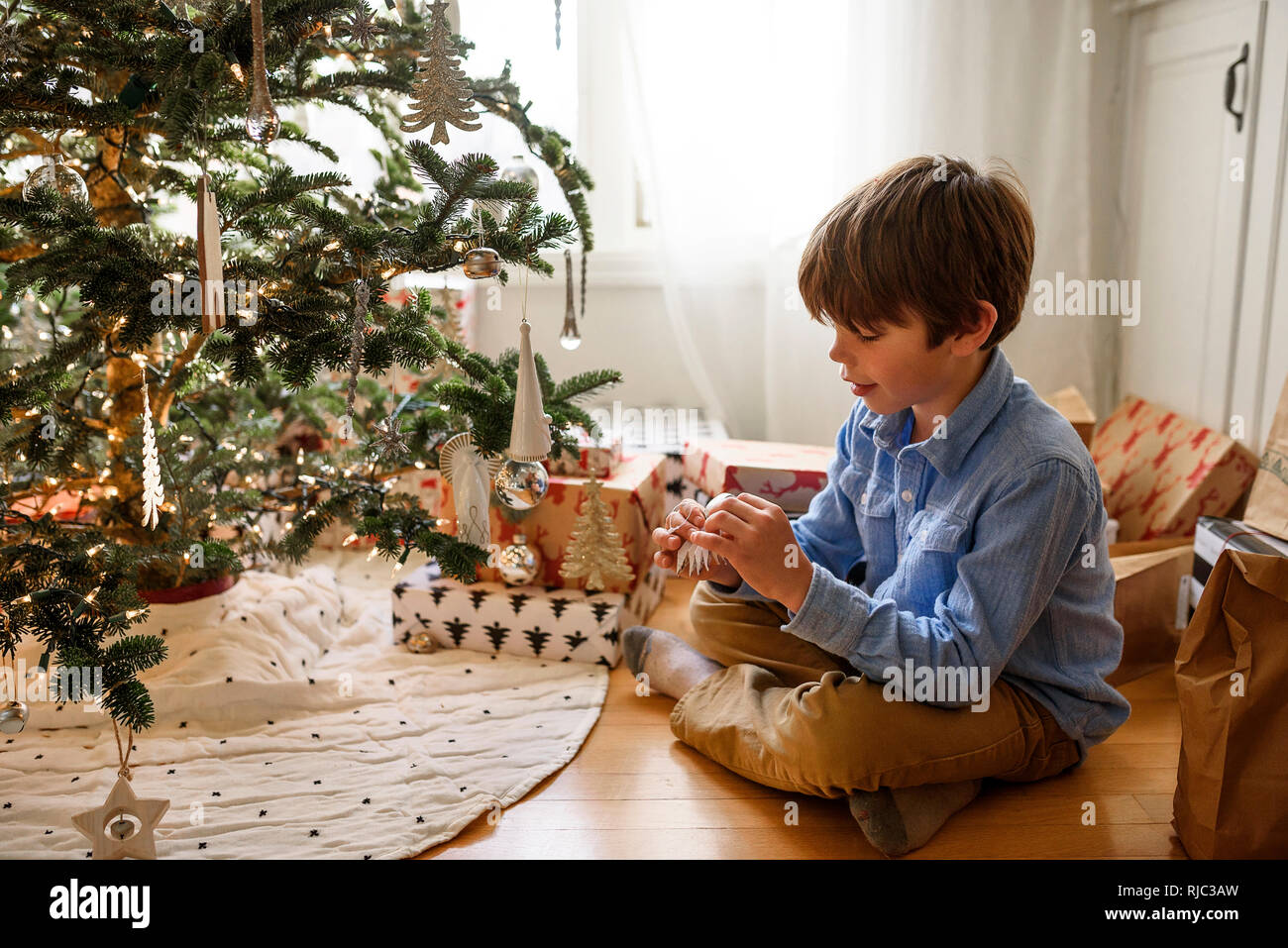 Ragazzo appeso decorazioni su un albero di Natale Foto Stock