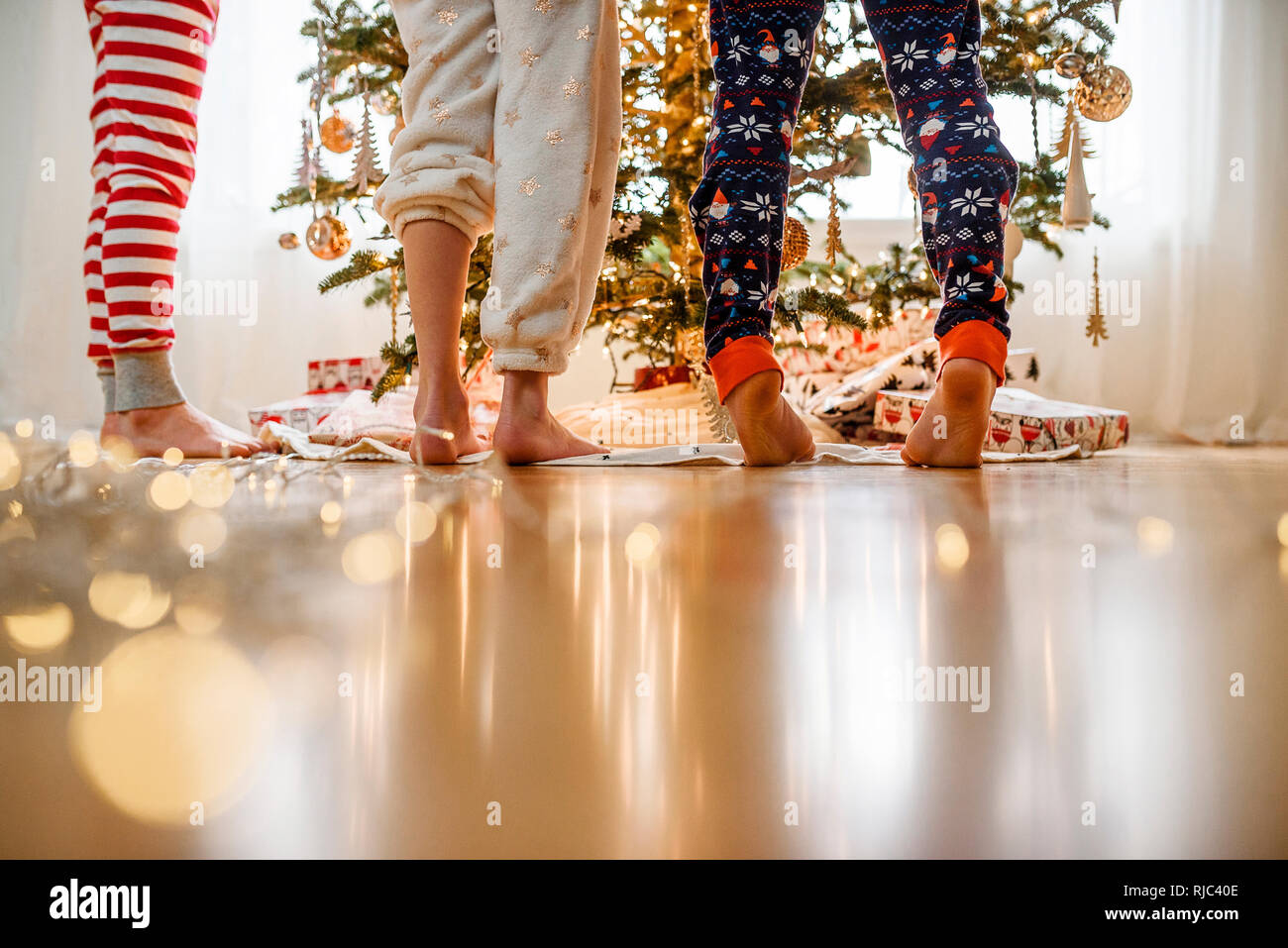 Close-up di tre bambini per le gambe mentre la decorazione di un albero di Natale Foto Stock