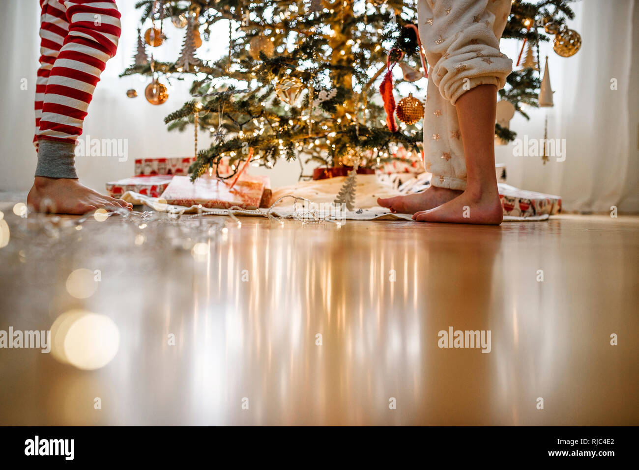 Close-up di due bambini per le gambe mentre la decorazione di un albero di Natale Foto Stock