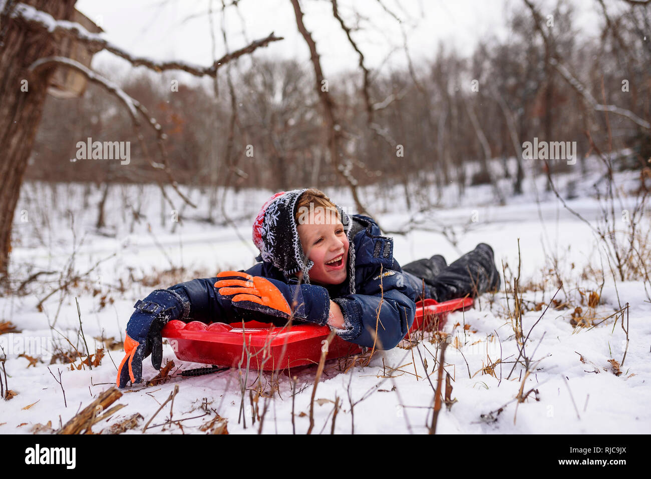 Ragazzo che giace su una slitta, Wisconsin, Stati Uniti Foto Stock