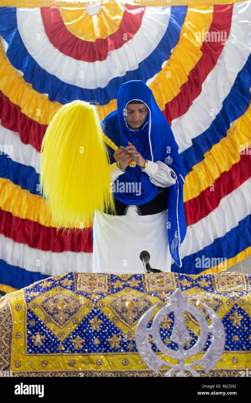 Una pia donna Sikh tenendo un Chaur Sahib che Ella farà onda il libro santo durante un servizio mattutino., a un tempio in Sud Richmond Hill, Queens. Foto Stock