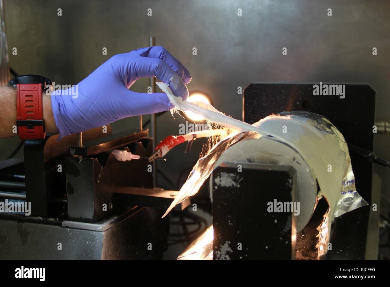 Uno scienziato da Edgewood chimico centro biologico (ECBC) separa il metallo-quadro organico (MOF) il materiale da una superficie in alluminio dopo electrospinning. Electrospinning diventa un liquido di soluzione di polimero in molti nanofibre che forniscono una superficie di deposito MOF. Foto Stock