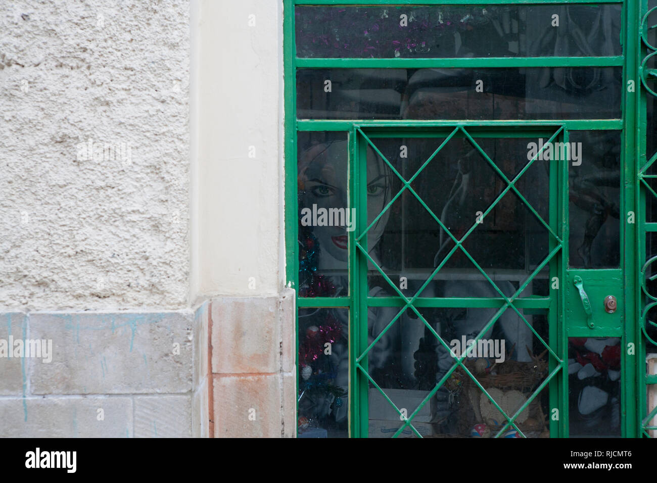 Guardando attraverso un vetro con cornice in metallo porta a un dipinto di una ragazza guardando nel piccolo negozio in Havana Cuba Foto Stock