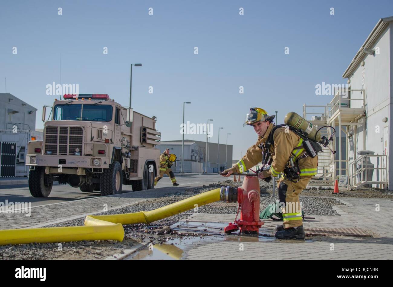 Stati Uniti Air Force Senior Airman Steven Werchek, 380 Expeditionary ingegnere civile Squadron pompiere, si allenta un idrante di fuoco ad Al Dhafra Air Base, Emirati Arabi Uniti, gennaio 12, 2018. I vigili del fuoco erano stati valutati in diversi modi per il trasferimento di acqua attraverso il motore fire. Foto Stock