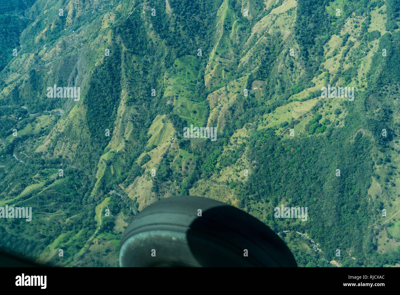 Un paesaggio foto di un aereo sopra la zona montuosa della valle centrale, Costa Rica. Un pneumatico di gomma del velivolo è visto in primo piano Foto Stock
