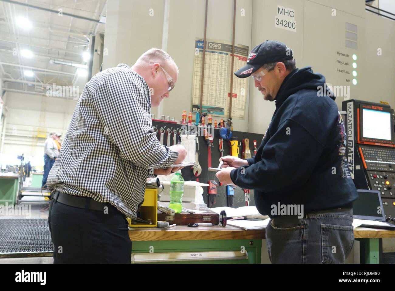 Giacobbe Phillips, Rock Island Arsenal congiunti di produzione e Technology Center quality assurance specialist, recensioni RIA-JMTC macchinista Kenneth Pennock estensimetri è in preparazione per il controllo della qualità la revisione della norma ISO 9001:2015 certificazione. Foto Stock