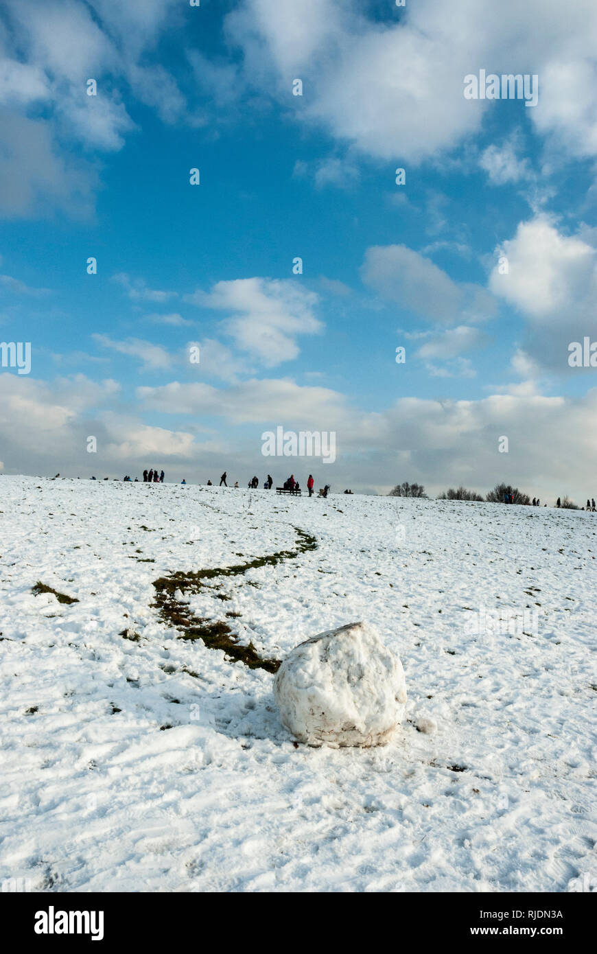 In primo piano un solitario gigante palla di neve ha rotolato giù collina del Parlamento lasciando una traccia visibile nella neve, in lontananza sono piccole figure Foto Stock