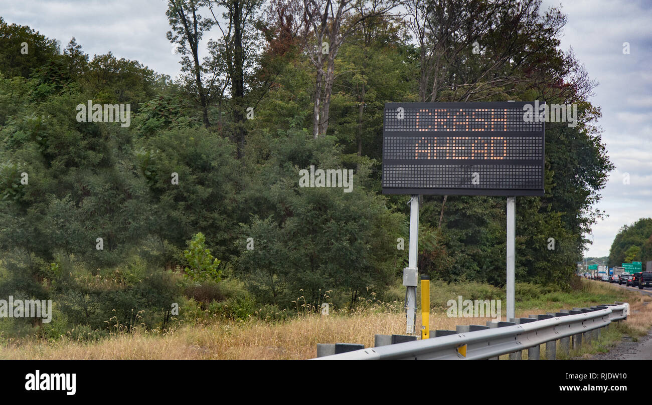 Un segno elettrico attenzione agli automobilisti di crash davanti con il traffico di backup. Foto Stock